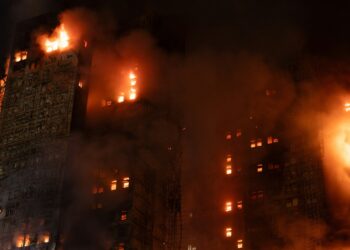 A tall building engulfed in flames at night