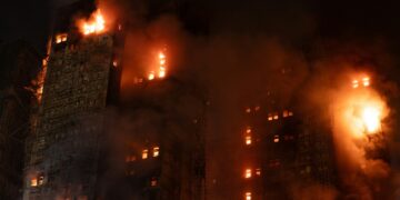 A tall building engulfed in flames at night