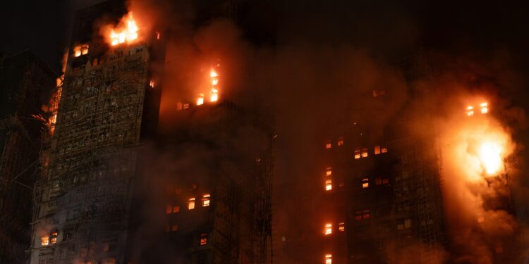 A tall building engulfed in flames at night