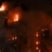 A tall building engulfed in flames at night